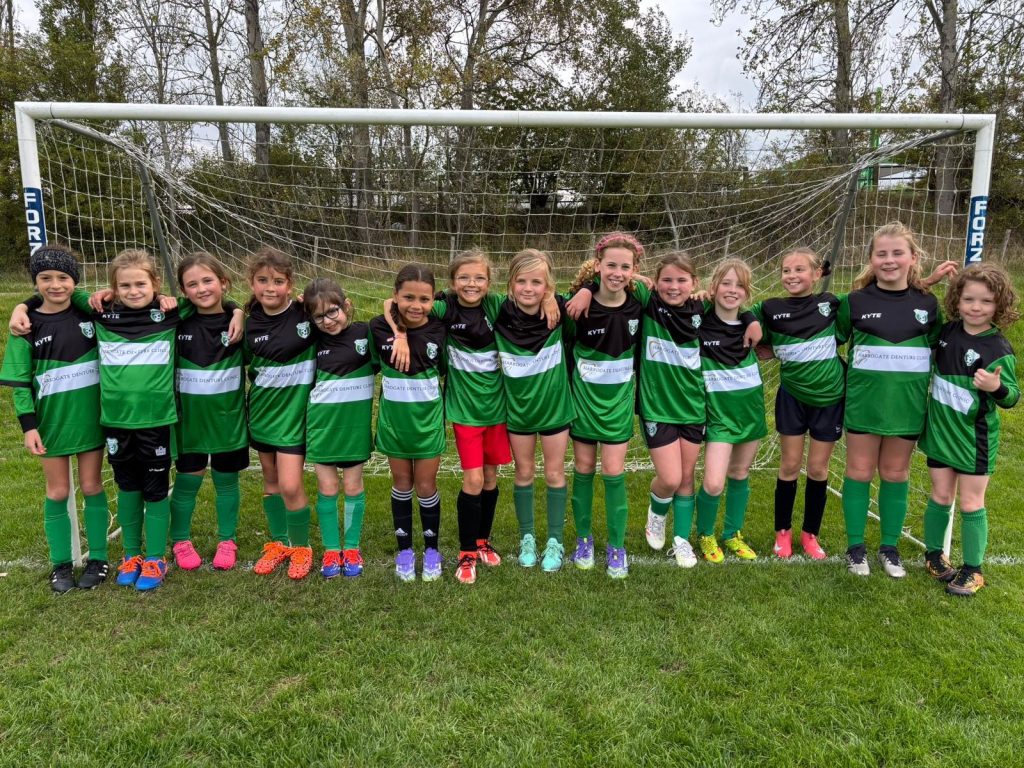 Girls football team posing in green uniforms